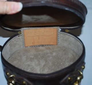 Mary Alice Parker round leather purse. It is dark brown with a tooled